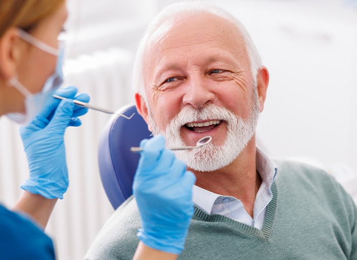 Dentist preparing to inspect an elderly man's teeth