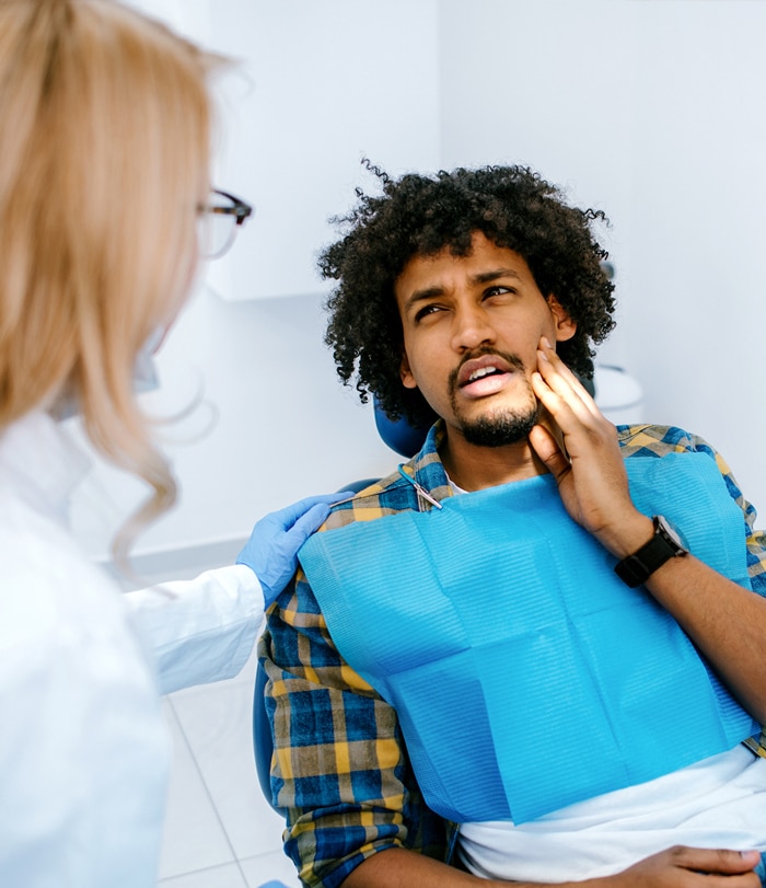Man rubbing her jaw in a dentist's office