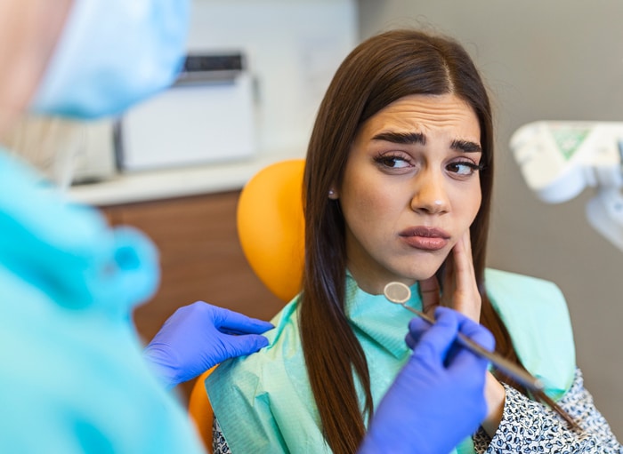 Woman rubbing her jaw in a dentist's office